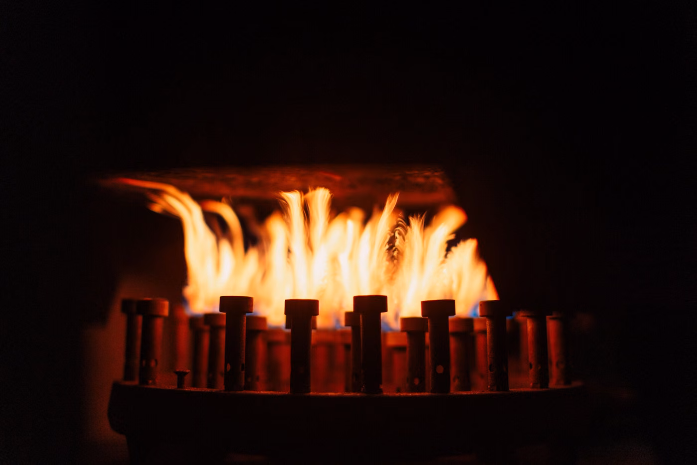Fiamma arancione di un bruciatore a gas su fondo scuro.
